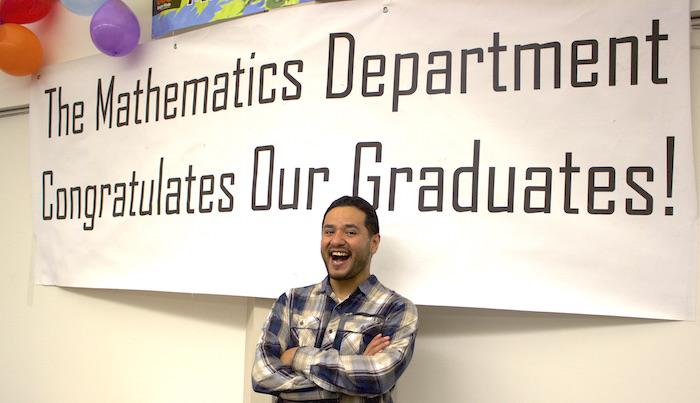 Micheal Lopez smiling under Math Graduate sign