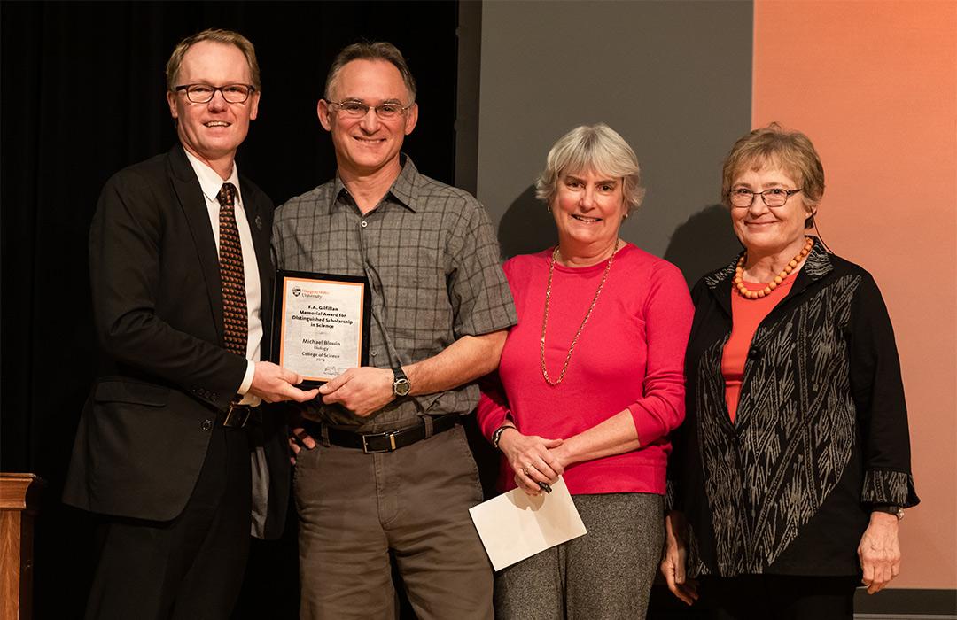 Michael Blouin receiving award from colleagues on stage