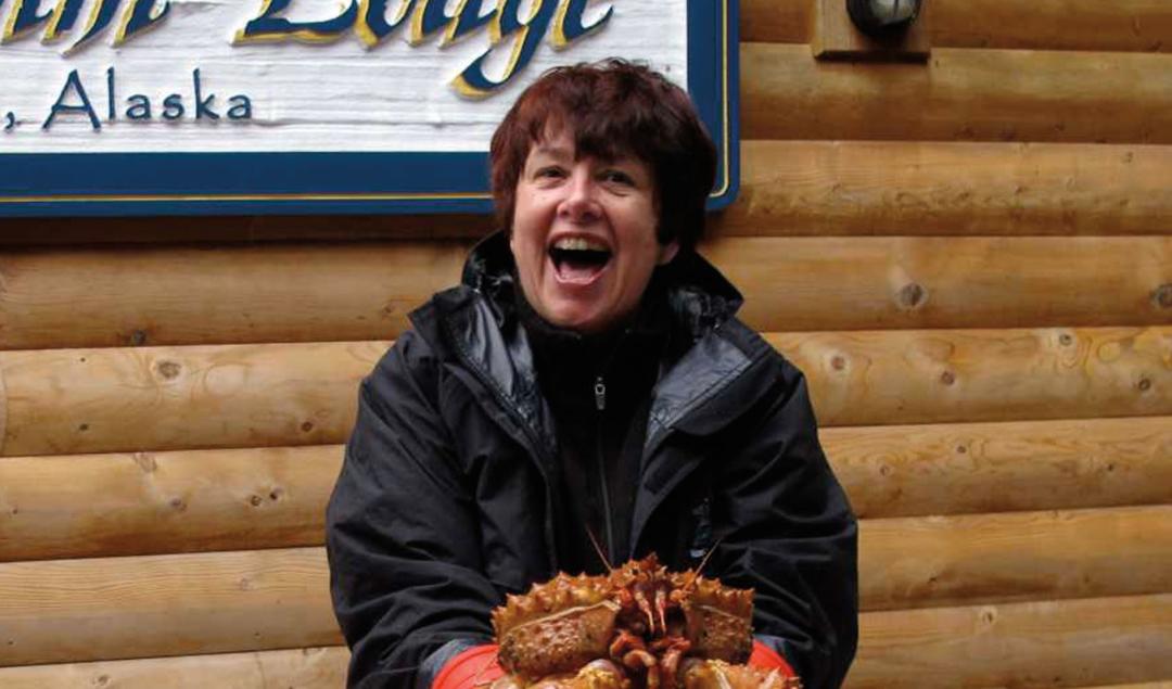 Judy Faucett smiling and holding a large crab