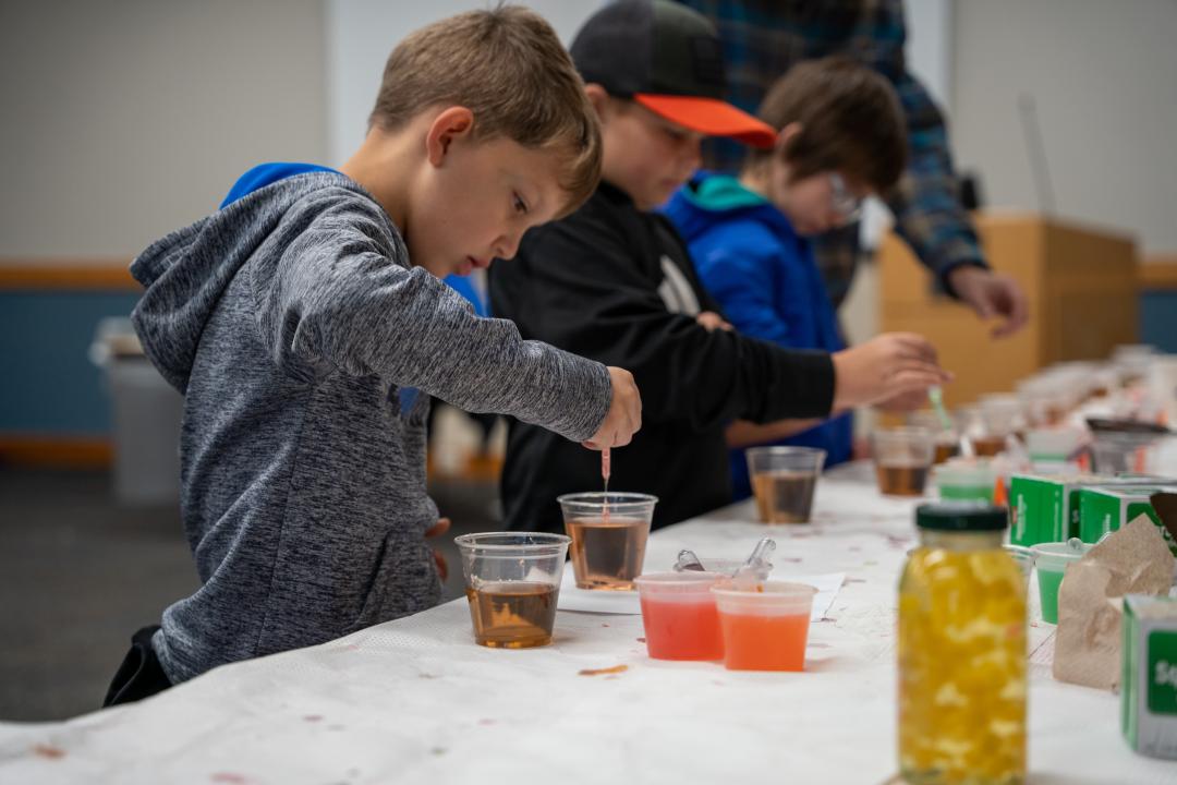 A student places drops into a colorful cup of liquid to make their own version of Orbeez.
