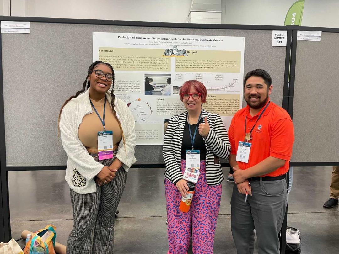 Biology undergraduate Amari Carter (left) shares her poster presentation with Associate Director of Student Engagement Gabs James (center) and Kameron Kadooka (right).