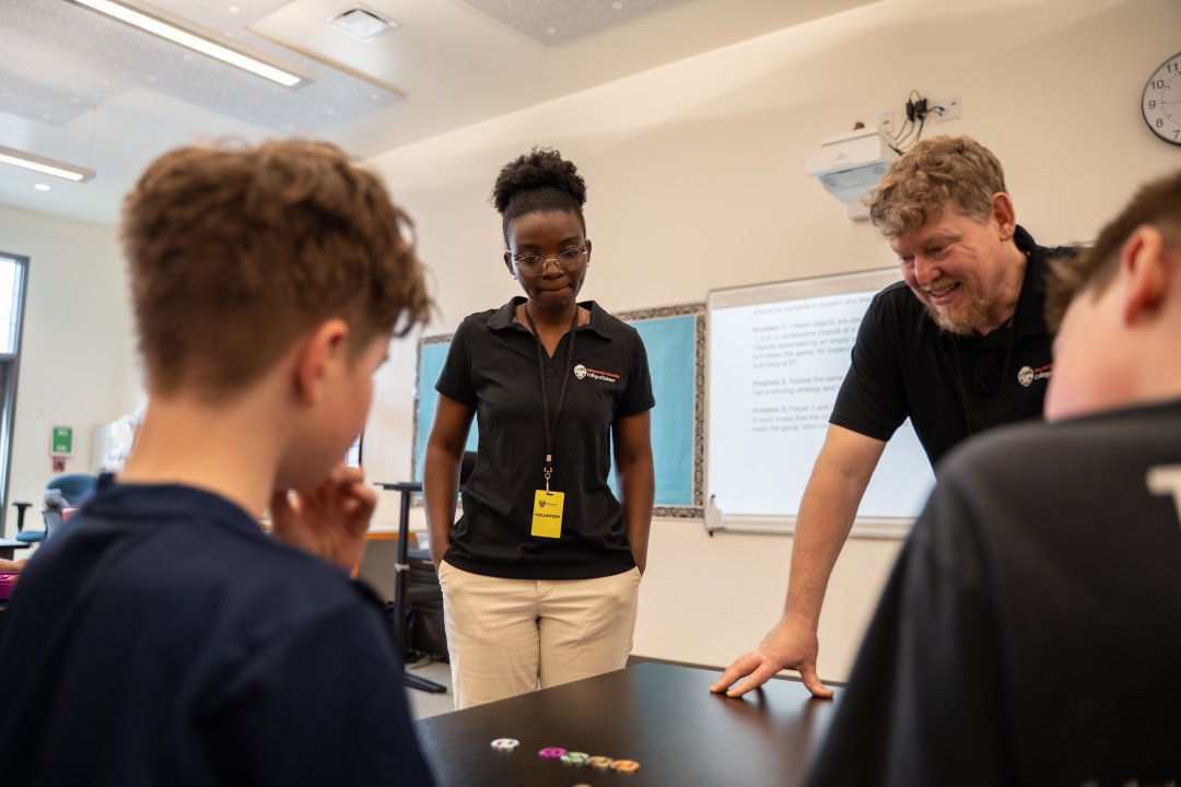 A woman and man talk to two students doing math.