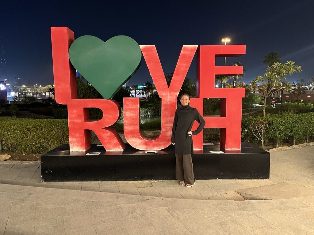 A woman poses with a giant sign that says "Love RUH."