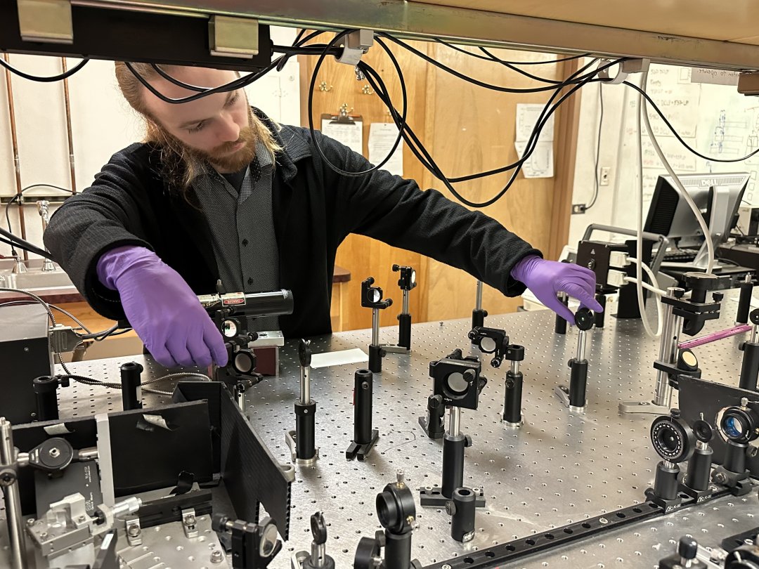 A man in a lab coat works with lasers.