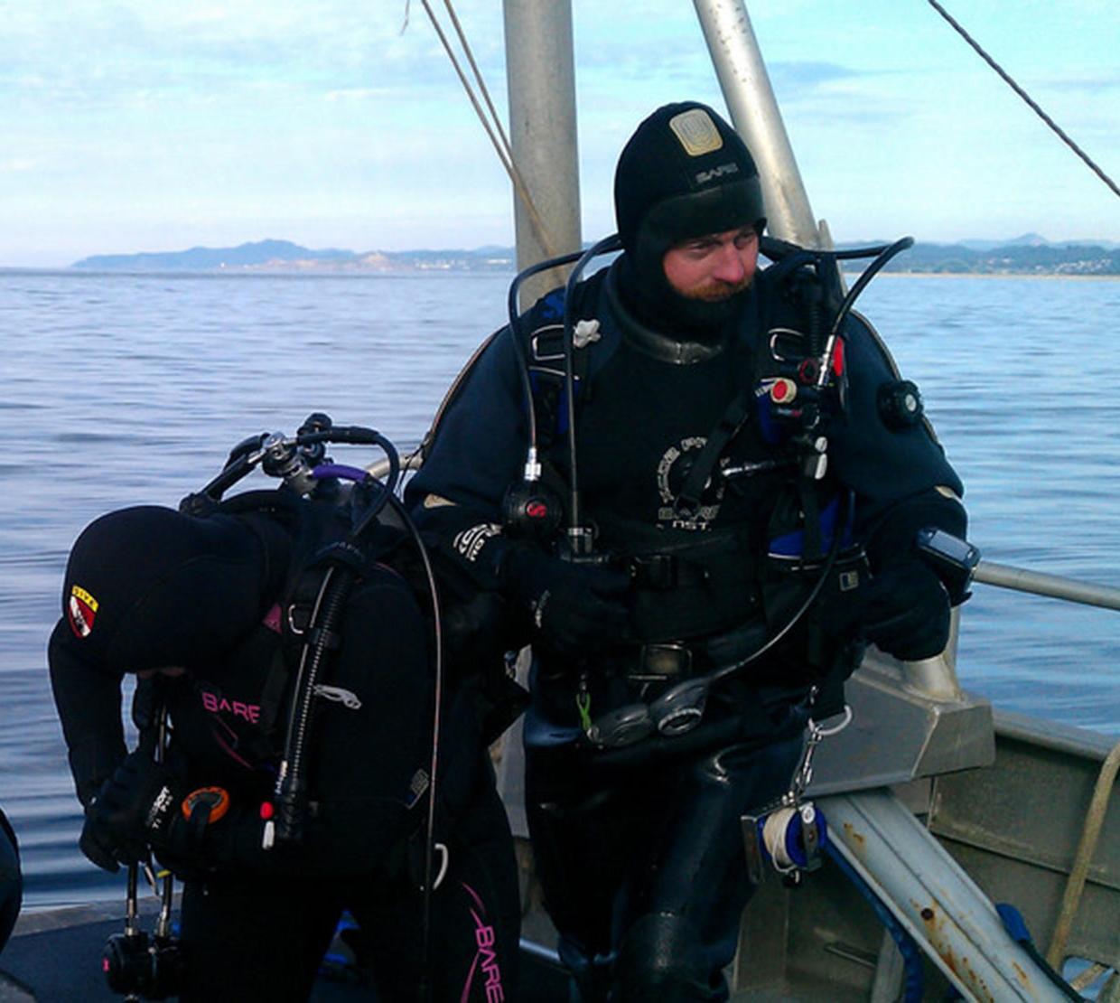 Scuba divers standing on edge of boat on sea