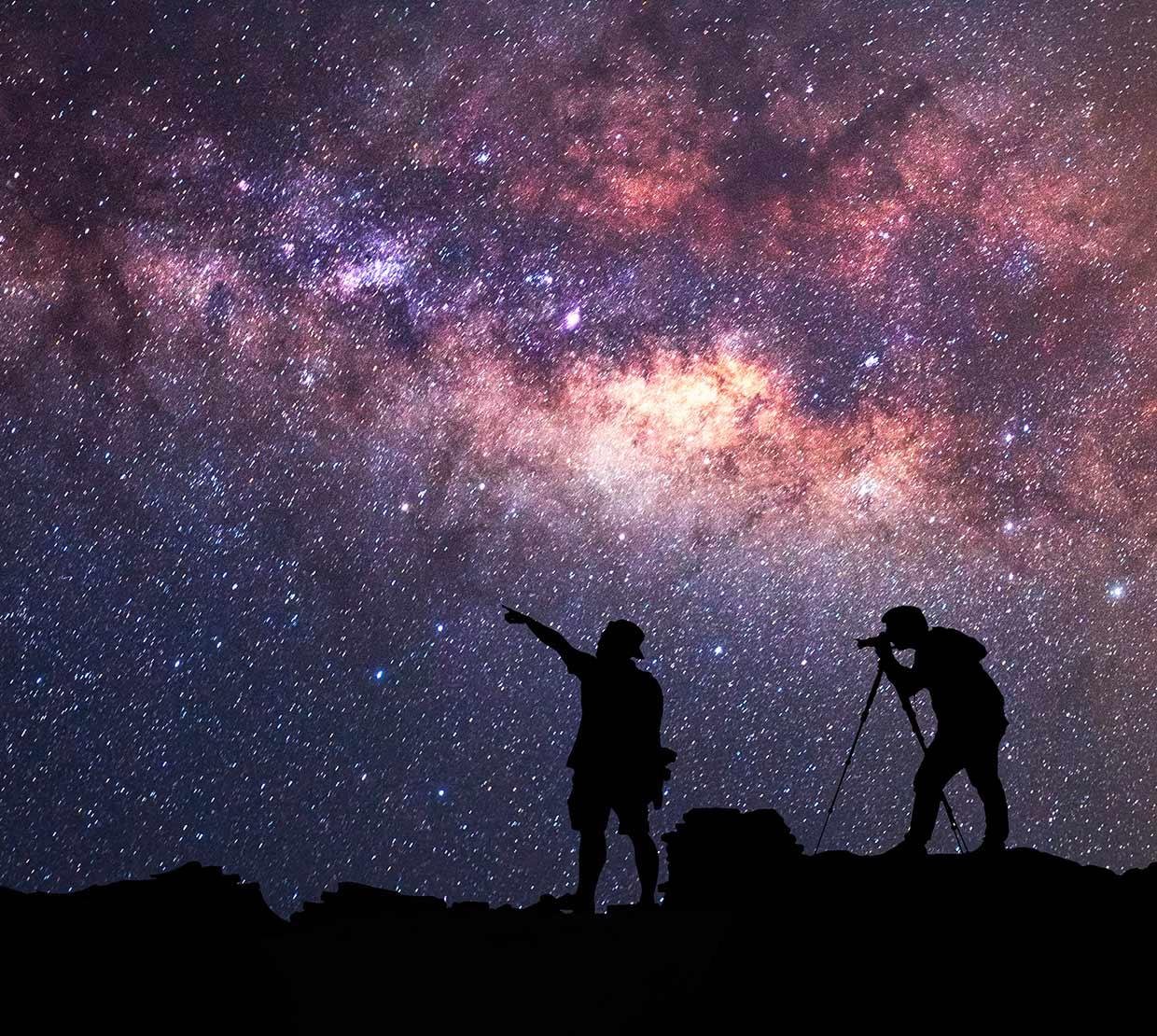 two silhouetted travelers gazing at stars