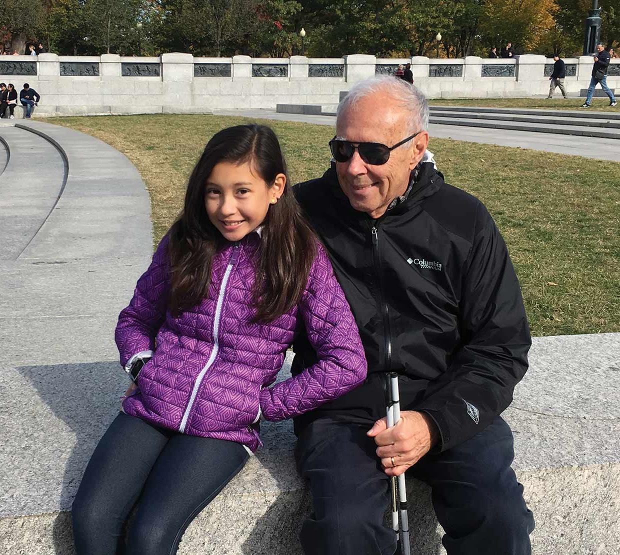 John Gardner with grand daughter sitting in a park