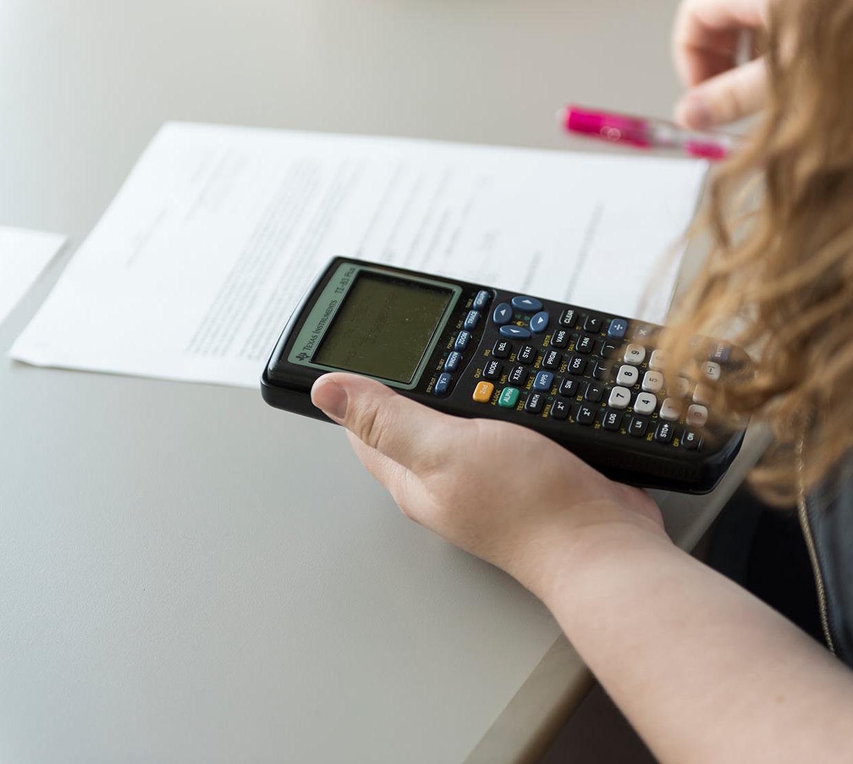 student working on math homework holding calculator