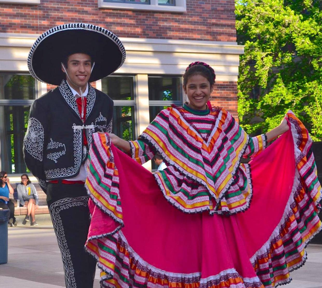 two students dressed in traditional Mexican festival garments in the SEC awning
