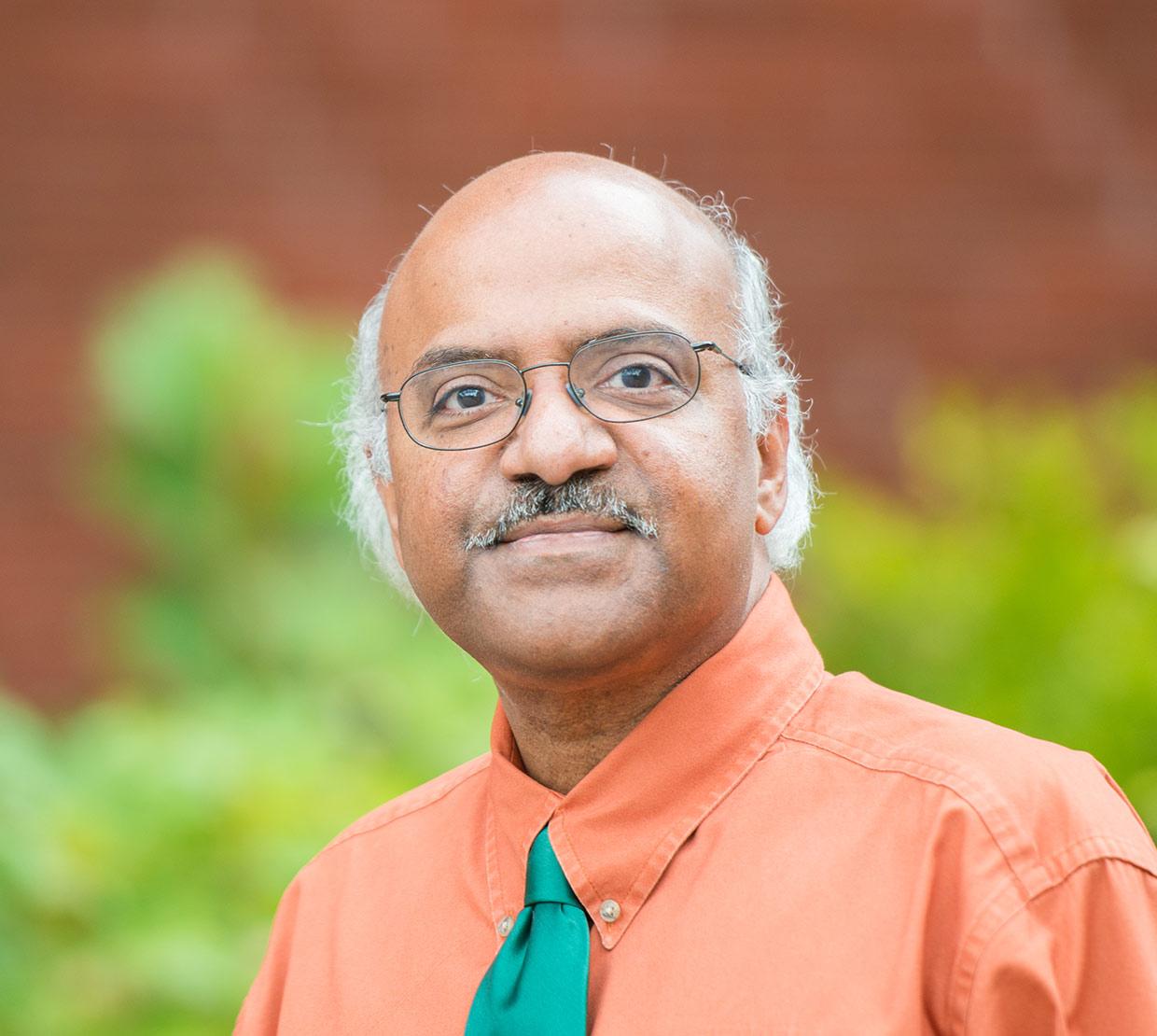 Sastry Pantula standing in front of shrubbery and brick wall