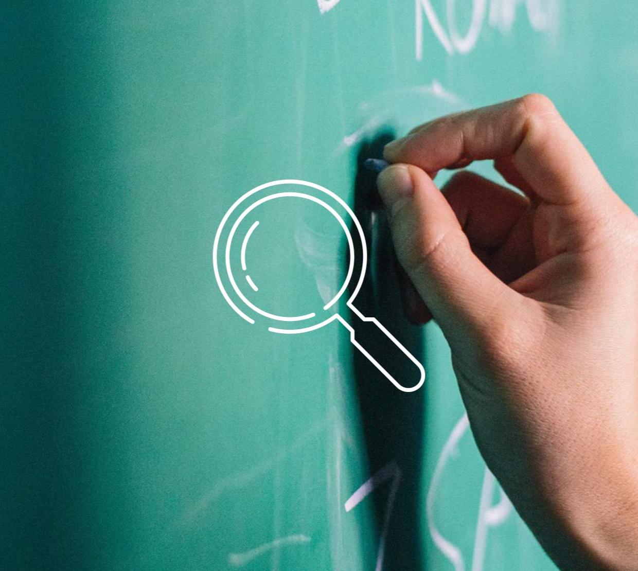 Magnifying glass icon above image of handing writing on chalkboard