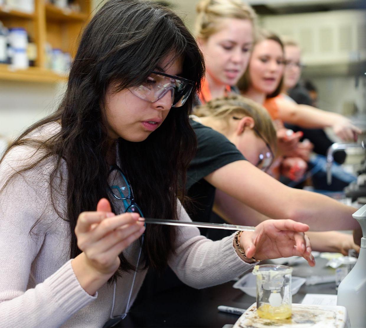 Young woman working in lab with other students.