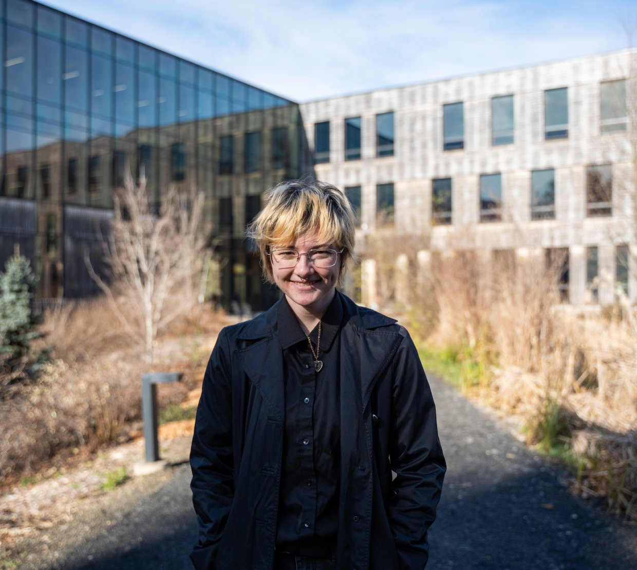 Head shot of an individual with short blonde hair wearing all black.