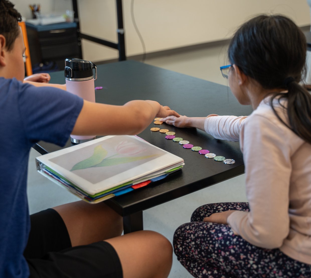 Two young kids work play with math tokens.
