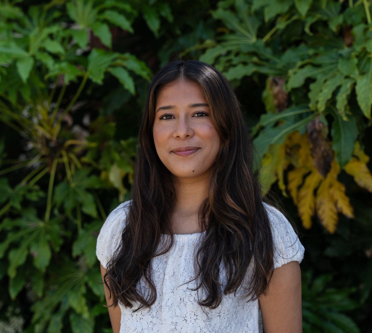 Maria Ruiz Cortes smiles for the camera in front of a green bush.
