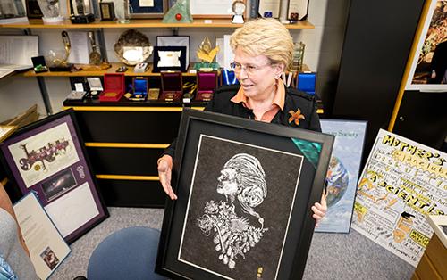 Jane Lubchenco holds up a portrait created by gyotaku artist Dwight Hwang using various marine species to apply the paint in addition to Lubchenco's own face. 