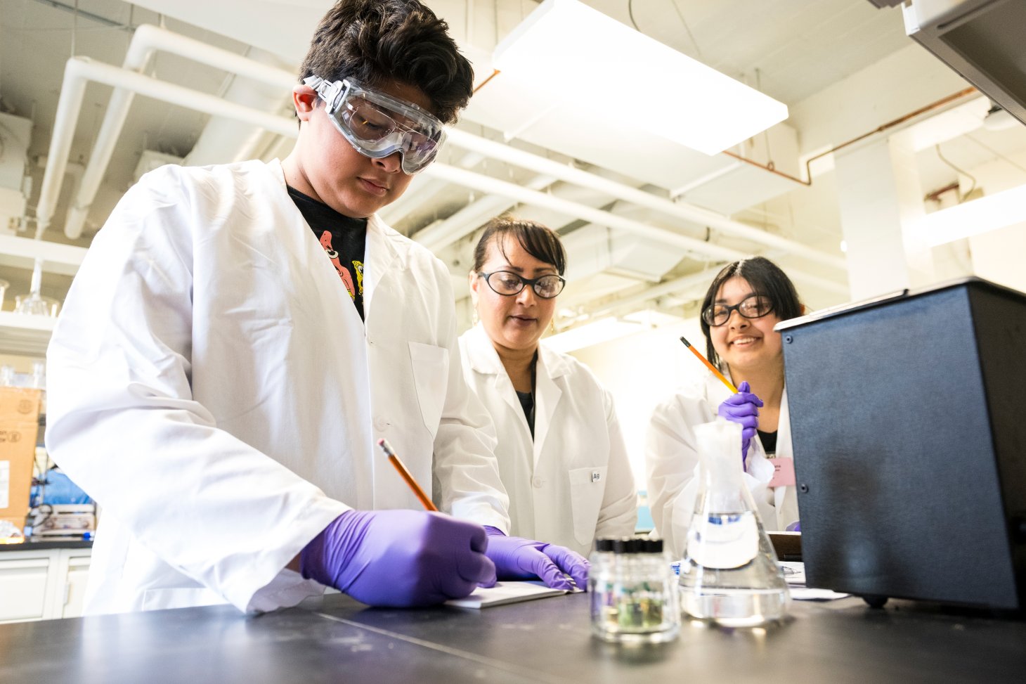 Marilyn Rampersad Mackiewicz mentoring two campers in their chemistry experiments in a lab at Oregon State University.