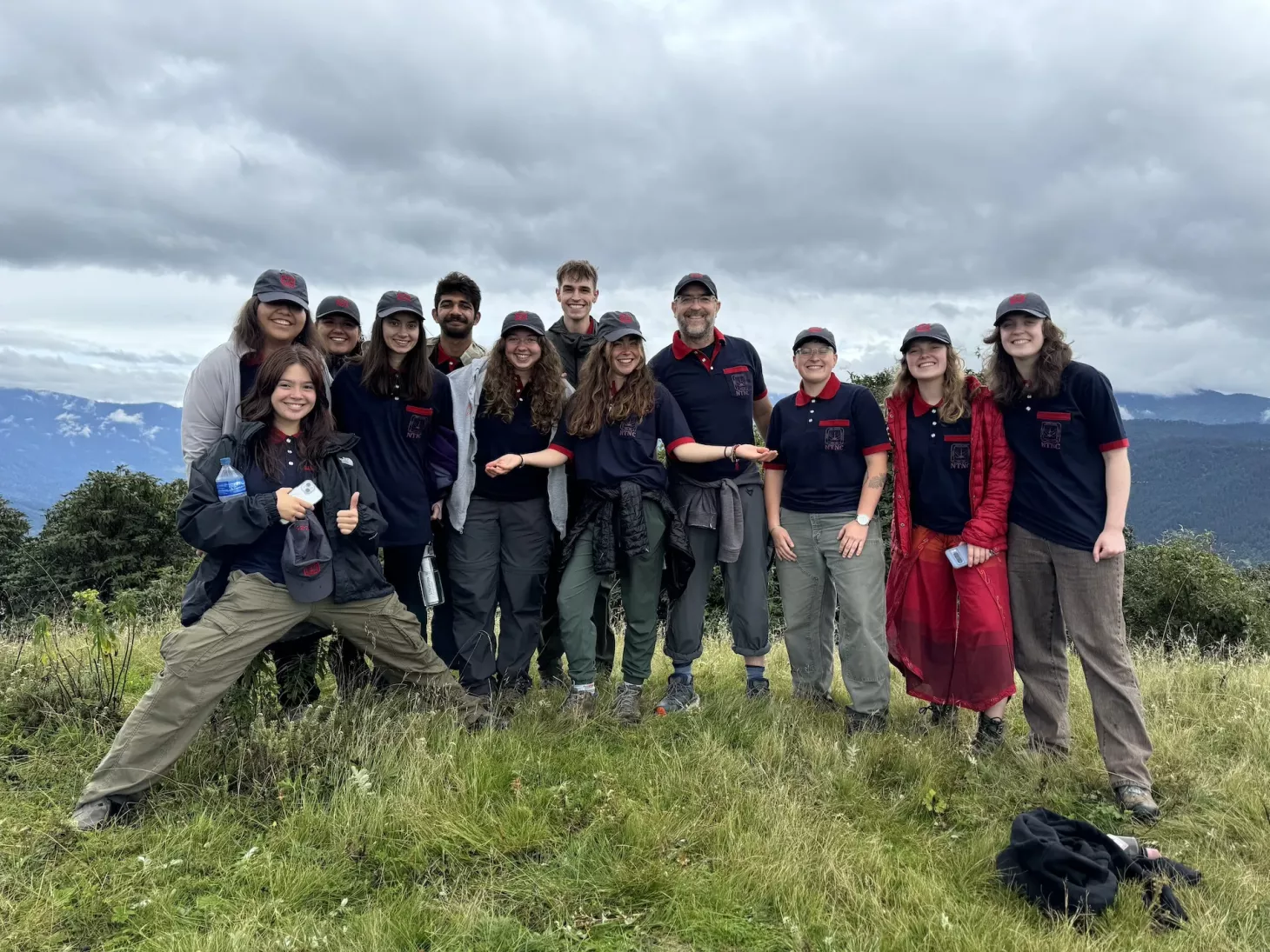 Group of study abroad students smile while standing on a grassy hill in Nepal.