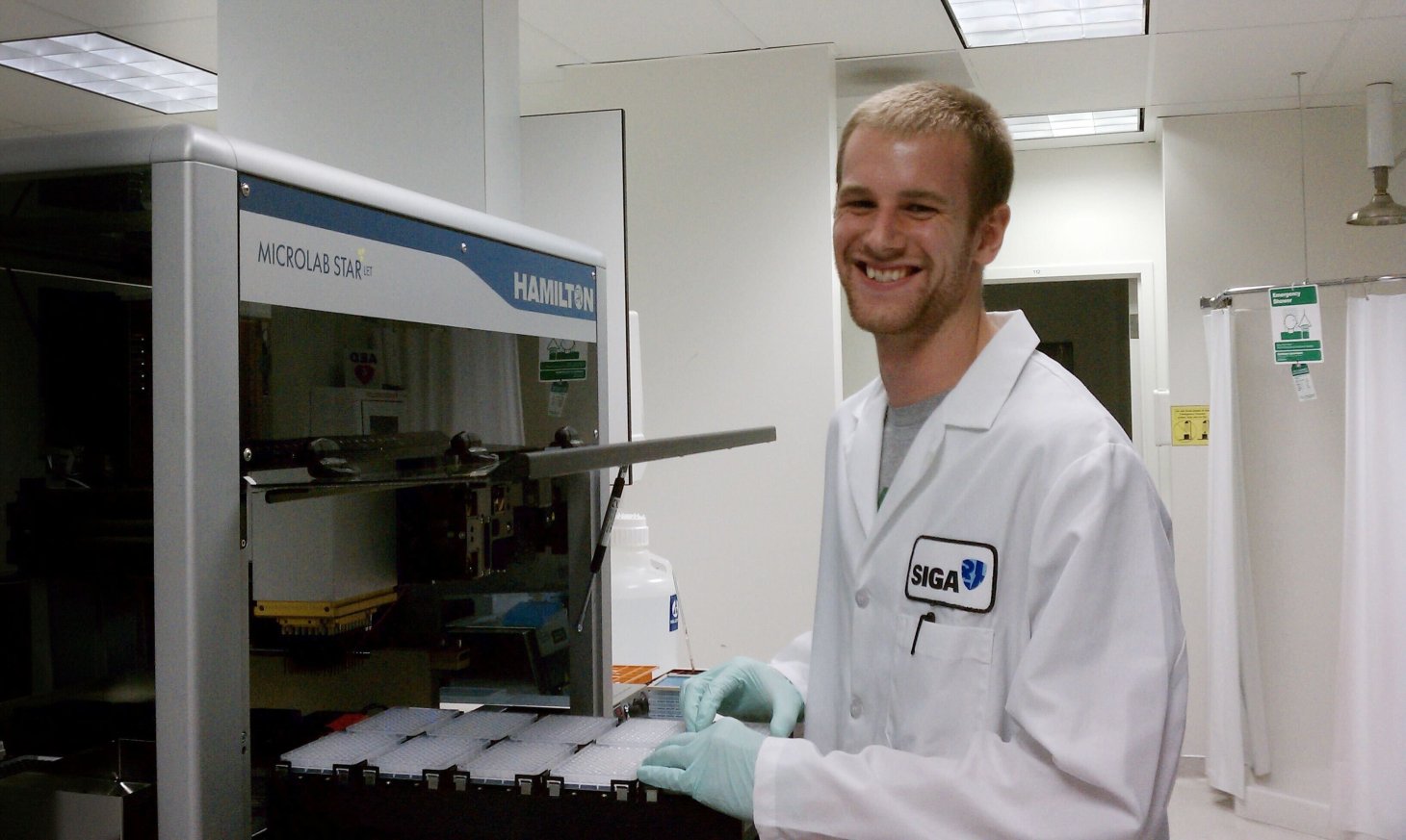 Jonathan Gallion in a lab coat operating an Hamilton Microlab STAR.