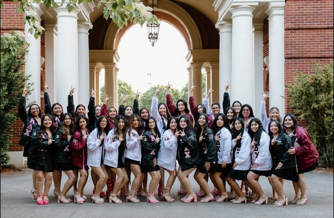 Maria Ruiz Cortes and a group of women form a celebratory crowd outdoors beneath the archway of Weatherford Hall.