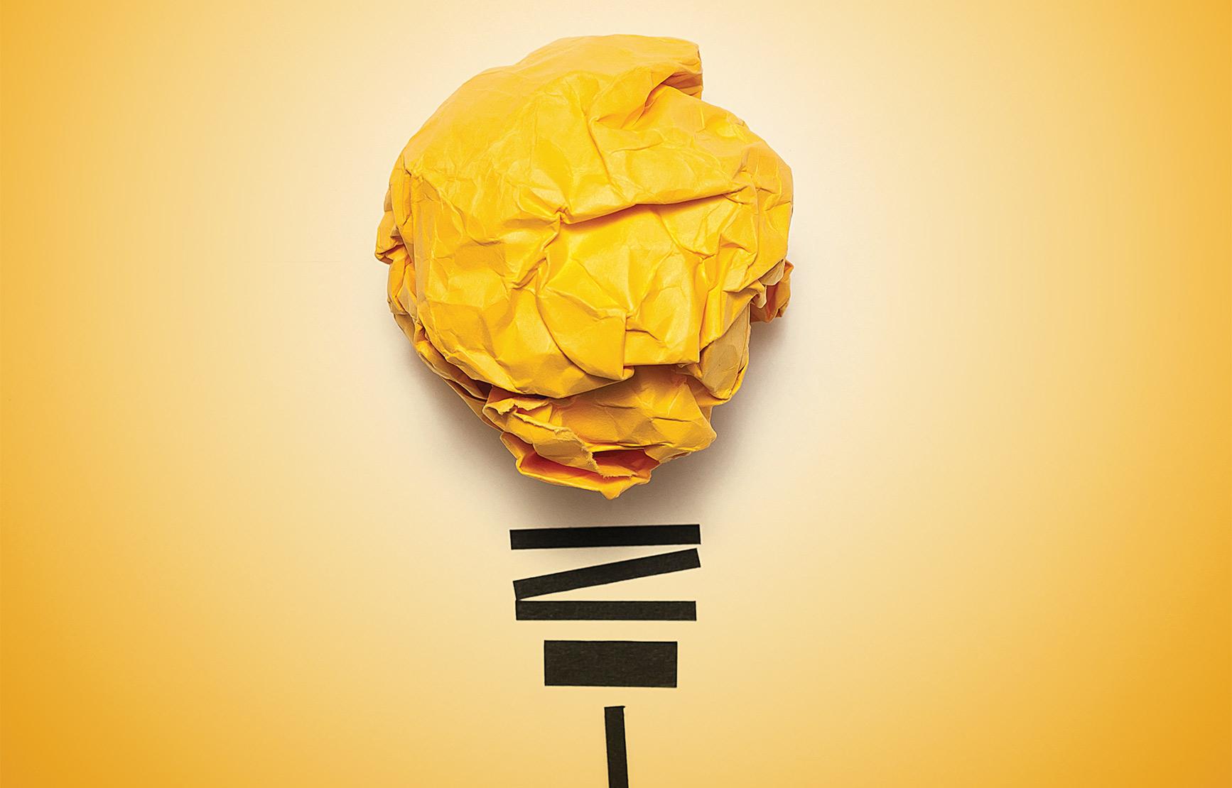 yellow crumpled paper and tape modeled as light bulb in front of yellow backdrop