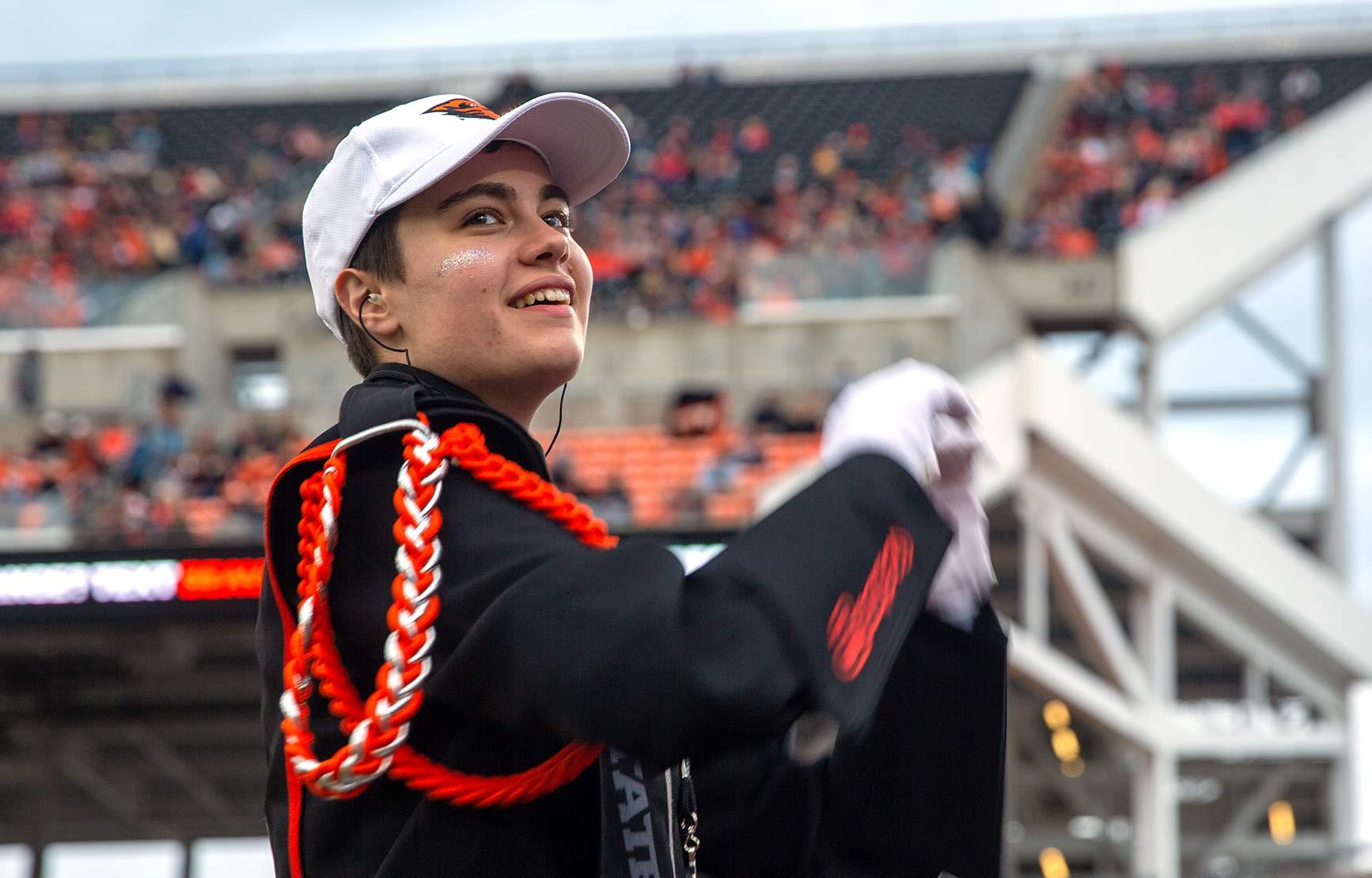 A young man conducts the Oregon State University marching band at a football