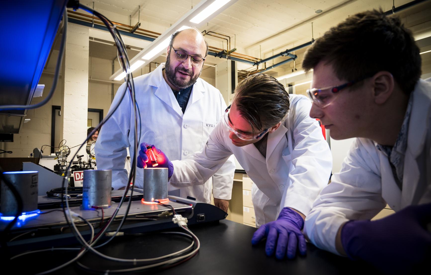 Two students working with Kyruakos Stylianou in his lab.