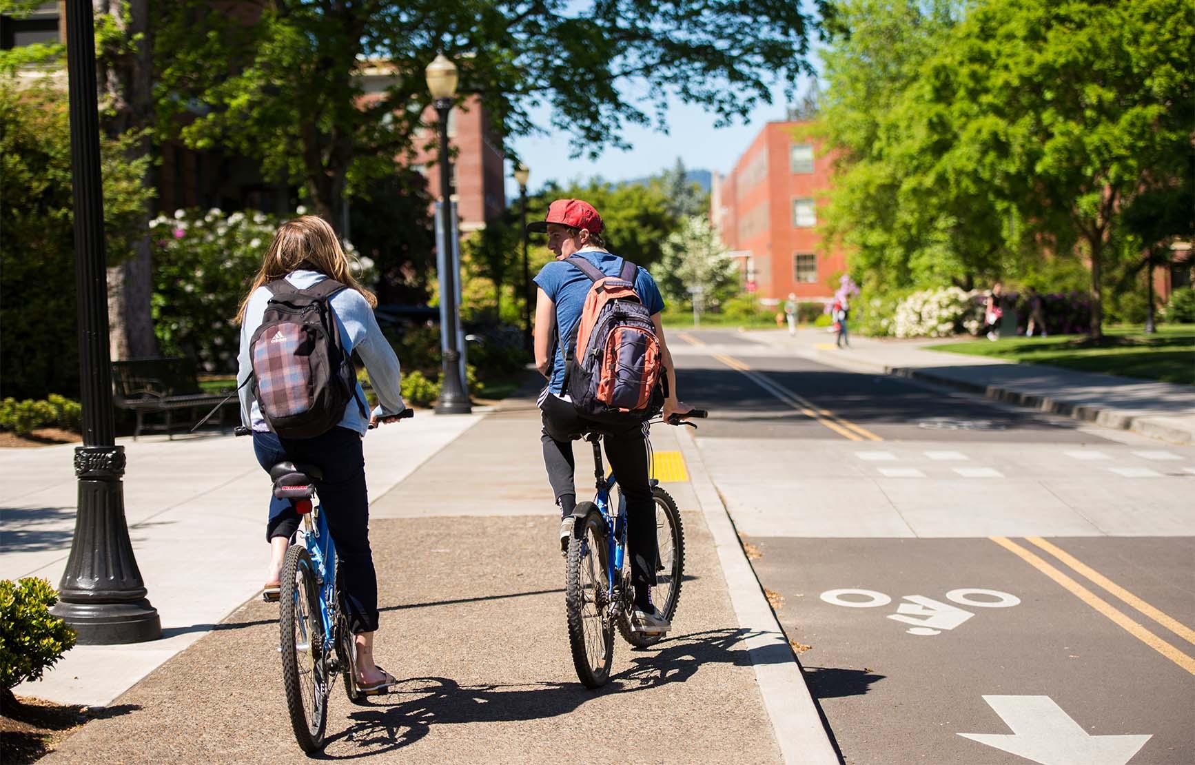 Two students biking on campus