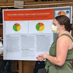 Student presents a poster on healthy dietary habits to attendees. 