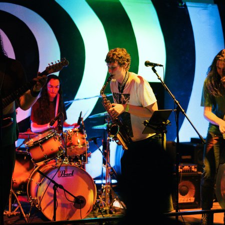 A group of musicians perform on a stage with instruments.