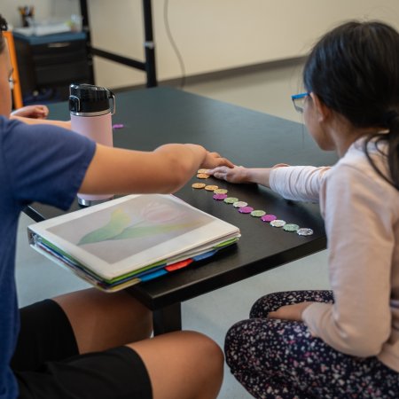 Two young kids work play with math tokens.