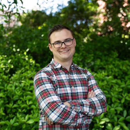 A man in a plaid shirt poses for a photo.