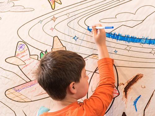 Child drawing with crayon on coloring book paper wall