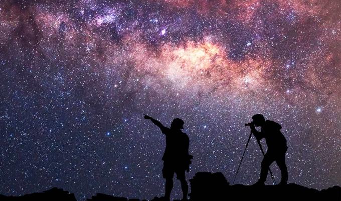 two silhouetted travelers gazing at stars