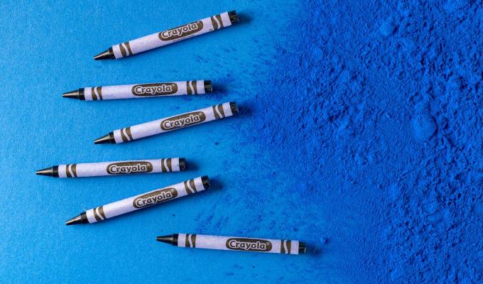 YInMn blue crayons on top of blue pigment texture