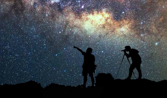 two silhouetted people watching the stars