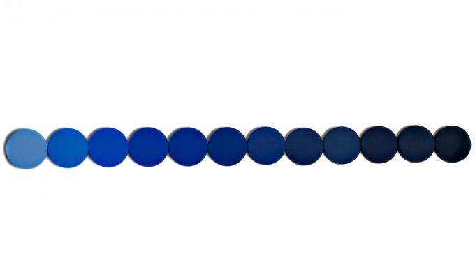 Blue pigment circles in a row on top of white backdrop