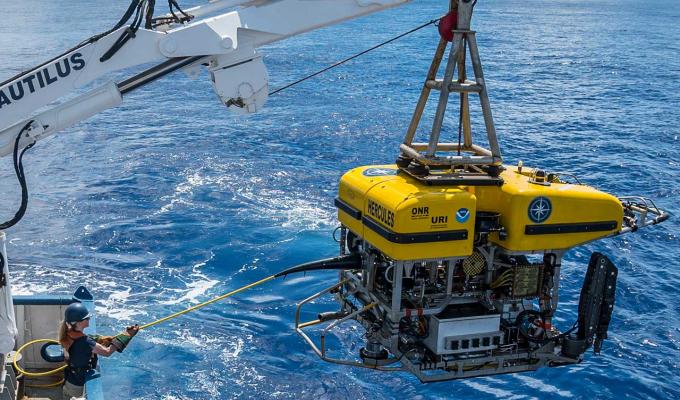 boat crane releasing research submarine into ocean