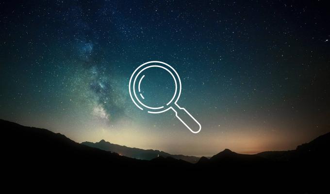magnifying glass icon above image of mountain ridge at night