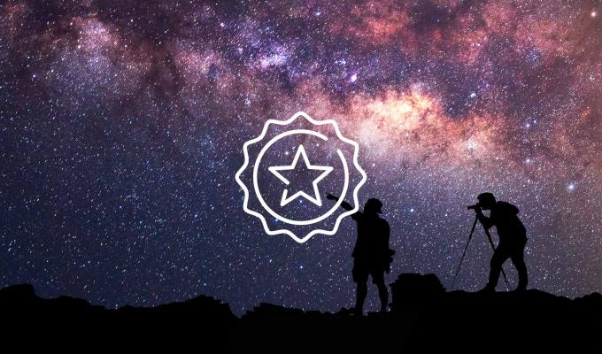 Star icon above starry night sky with two silhouettes of explorers