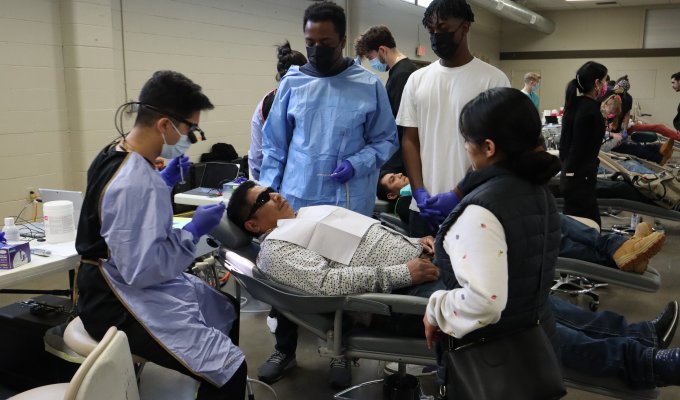 Students help a community member receive dental care.