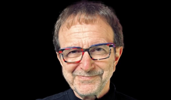 Vincent Racaniello wears a black shirt on a black background. He smiles slyly.