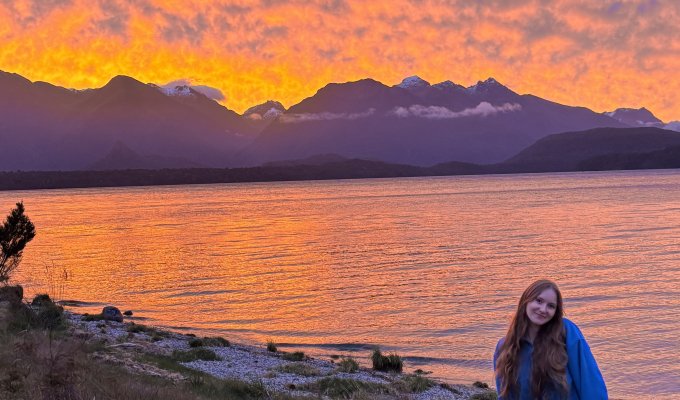 A woman stands in front of a sunset.