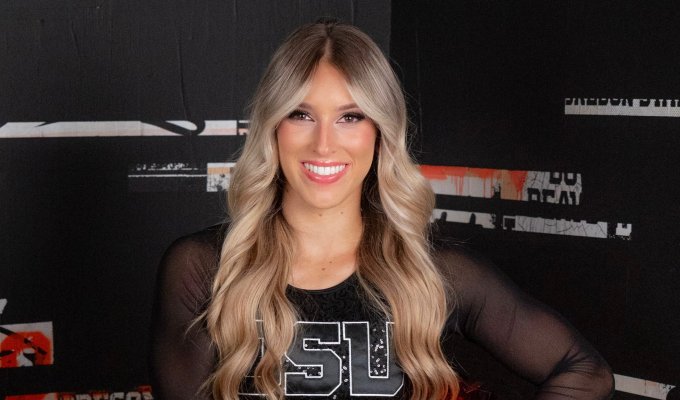 A headshot of a woman with wavy blonde hair smiling at the camera wearing a black OSU cheer uniform. 