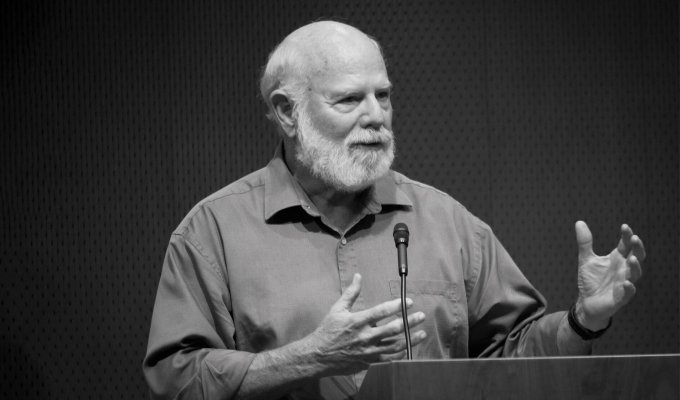 Image of Stevan J. Arnold: A male professor in short sleeve button-up shirt speaking at a podium.