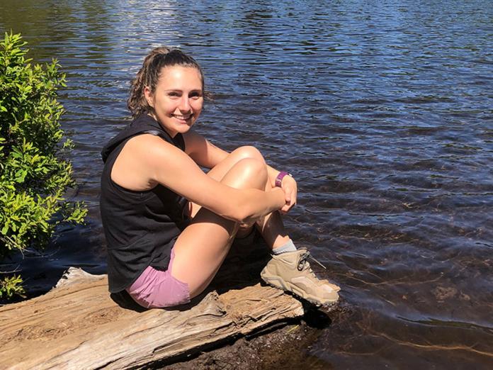 Karissa Renyer sitting on log along a lake shore
