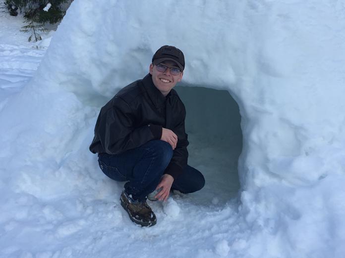Kyle Jones sitting in front of snow igloo