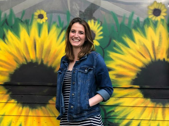 Rebekah Huckaby standing in front of sunflower mural
