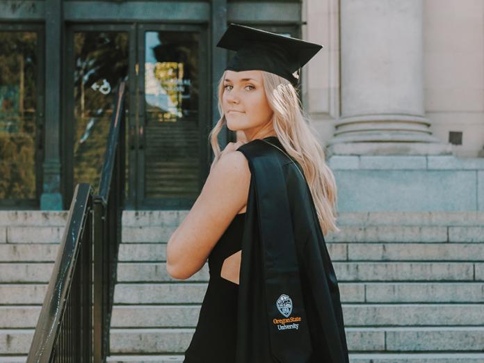 MaKenna Dahl wearing graduation cap and stole on the Memorial Union entrance steps.