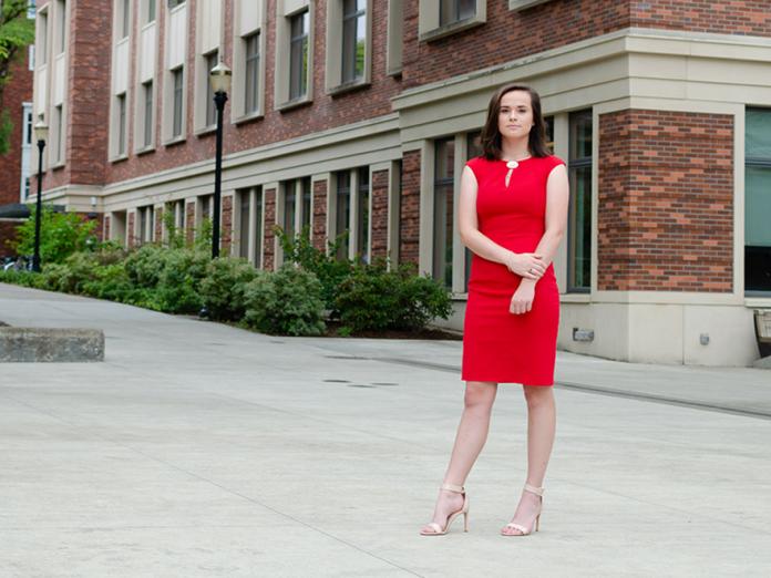 Rachel Josephson standing in Student Experience Center (SEC) Awning in red dress.